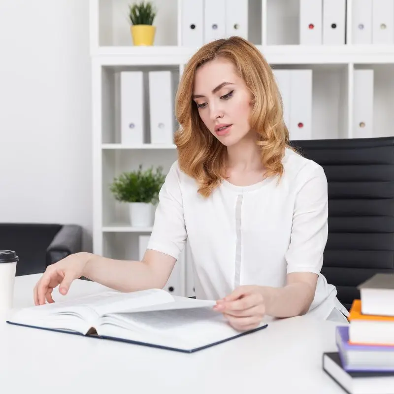 A young lady looking over books in her office for research