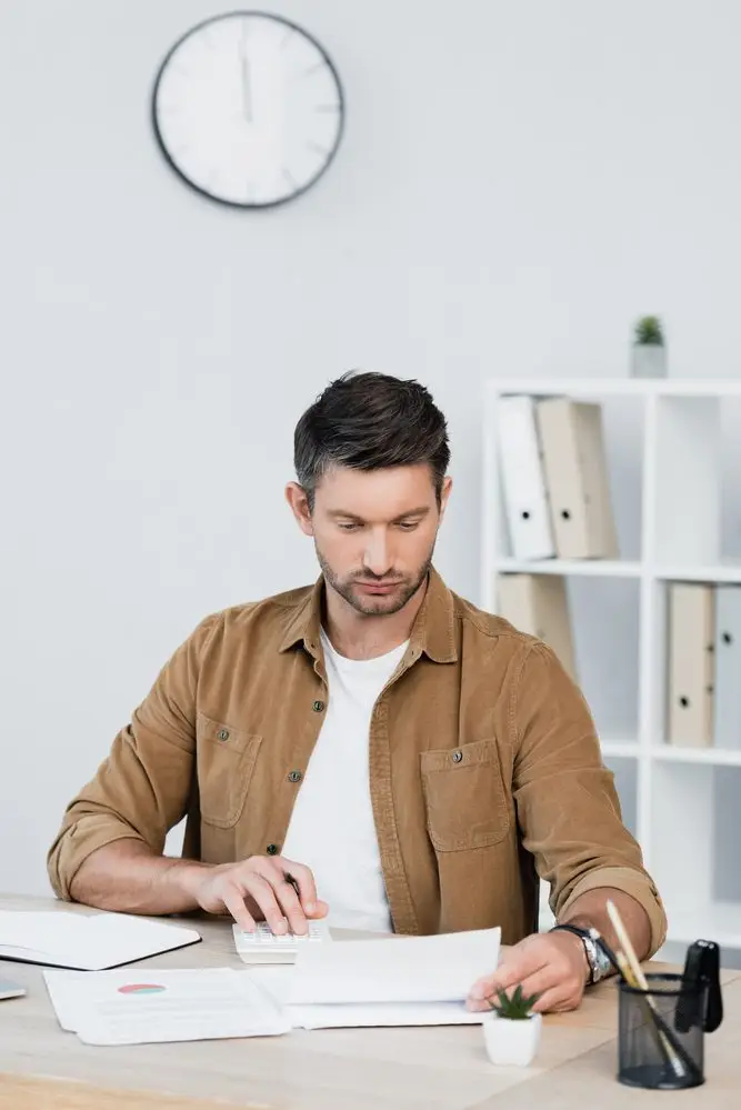 Focused businessman looking at paper sheet while sitting at his desk