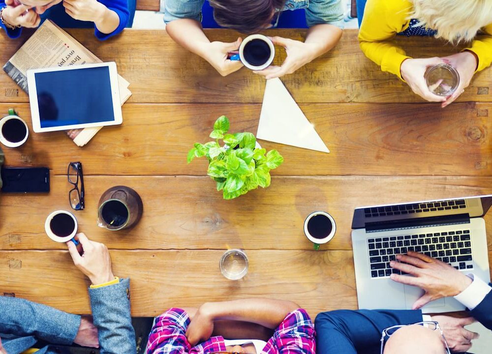 Overhead shot of startup employees at startup discussing business at a table