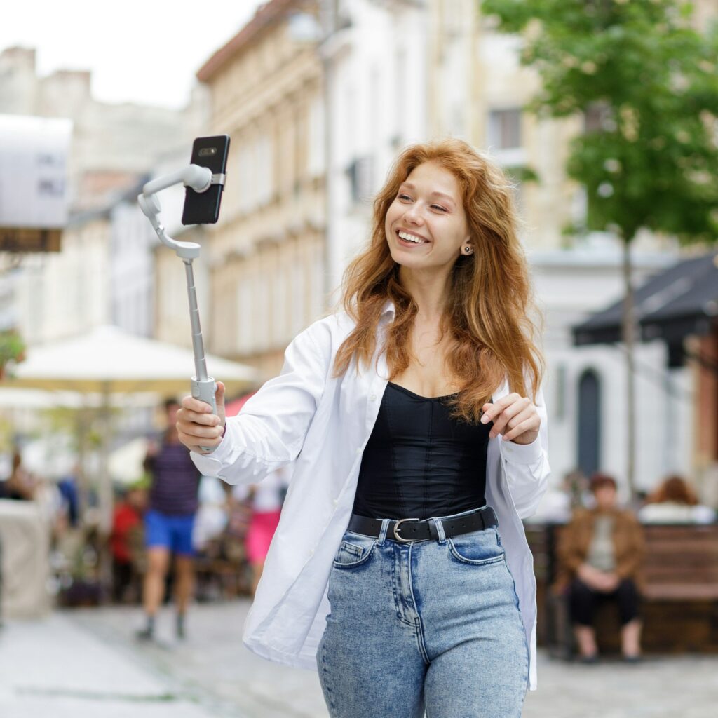 Young redheaded beautiful woman walking and using her mobile phone